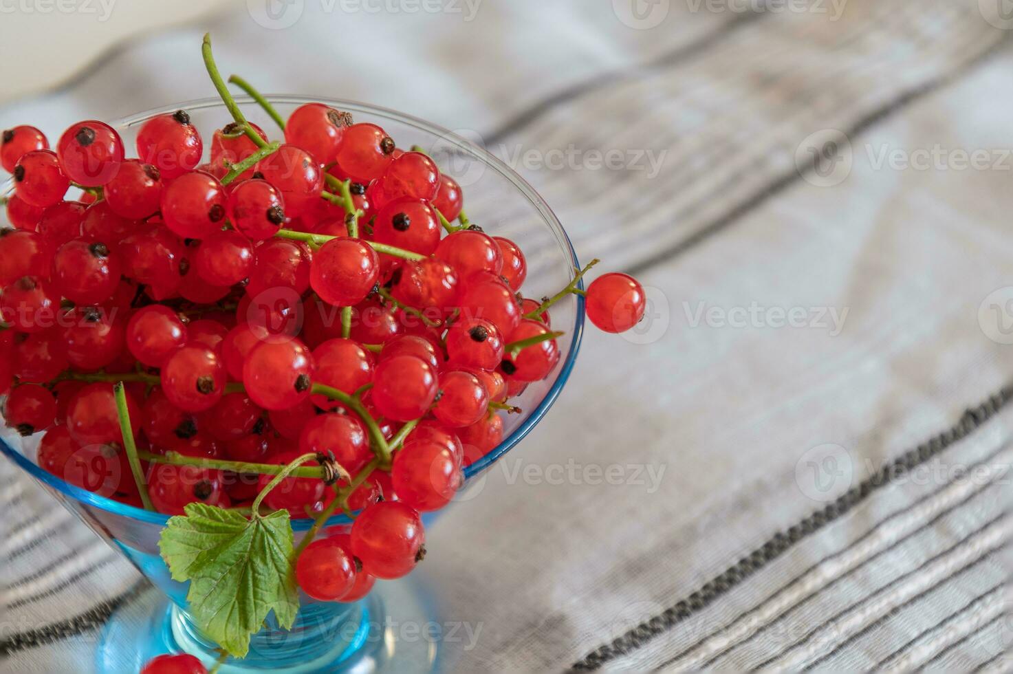 Red currant closeup on the twigs in a transparent vase on a linen blanket photo