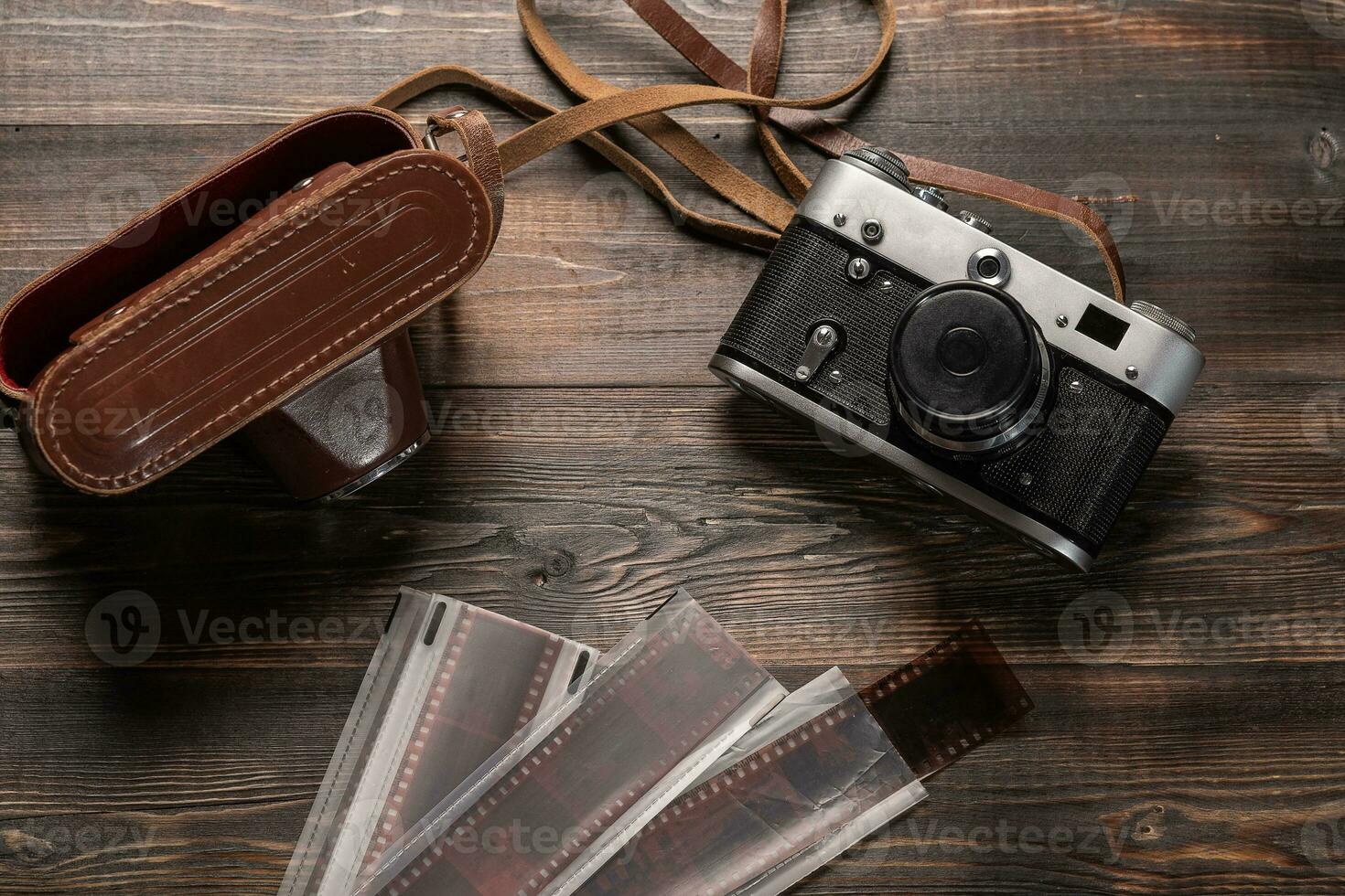 Vintage film camera with leather case and photographic film on dark wooden table. The view from the top photo