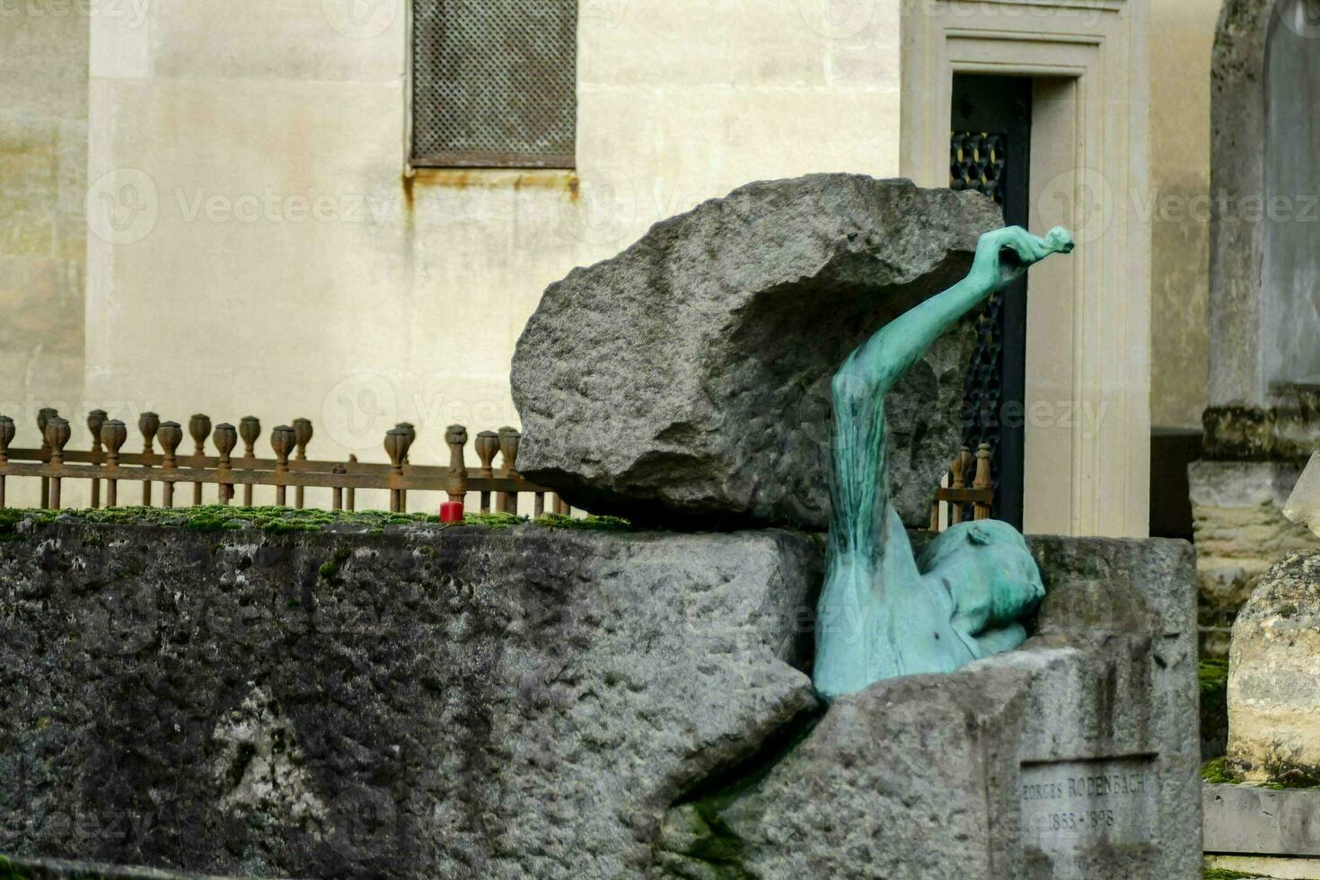 a statue of a man in a rock in front of a building photo