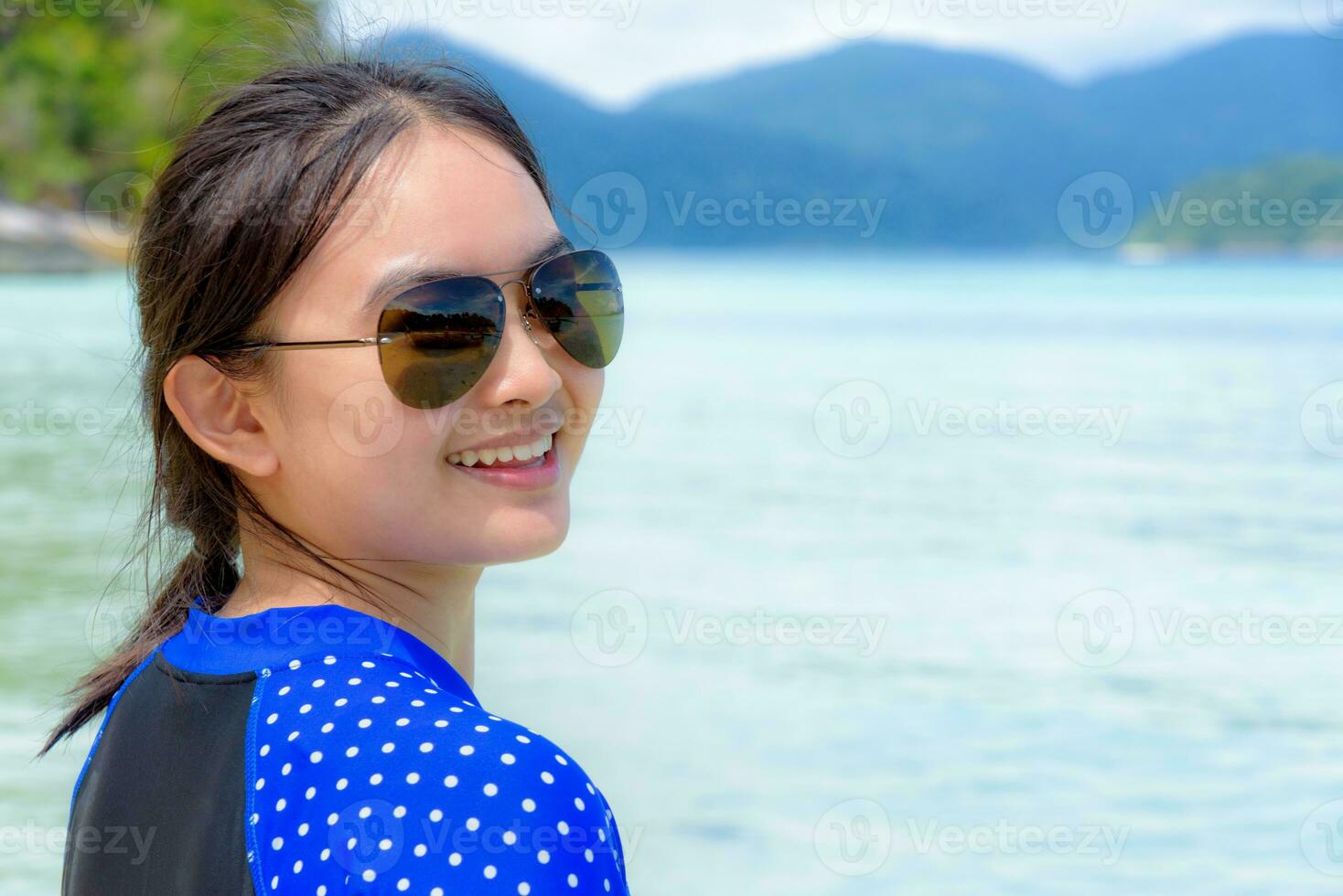 Face of a woman is smiling at the camera on the sea background photo