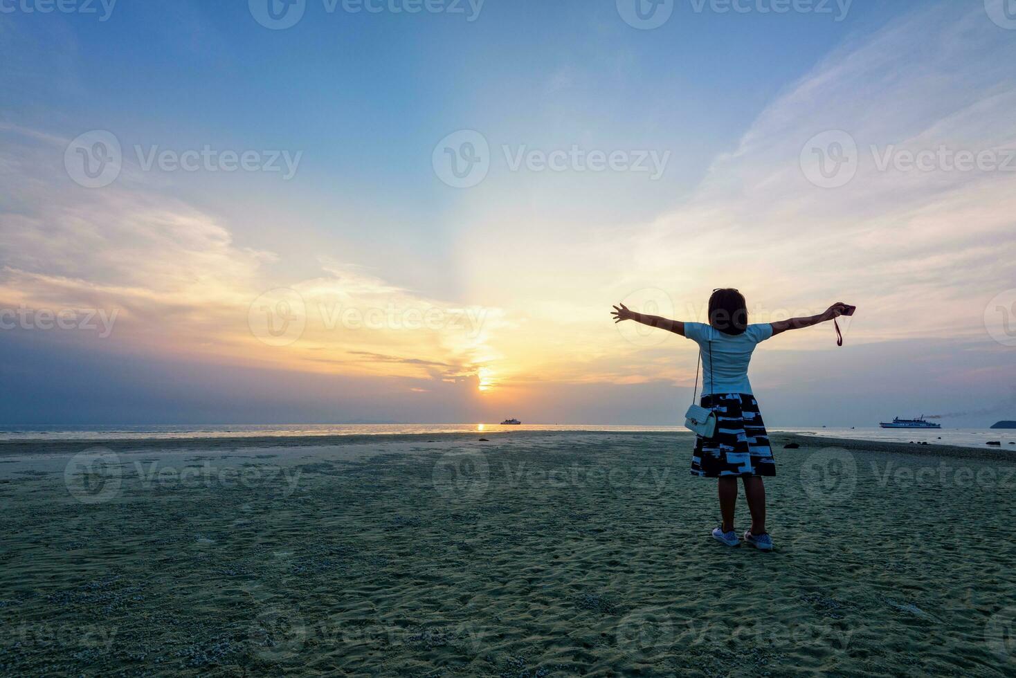 Woman standing arms outstretched at sunset photo