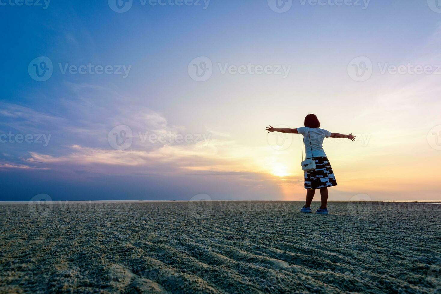 Woman standing arms outstretched at sunset photo
