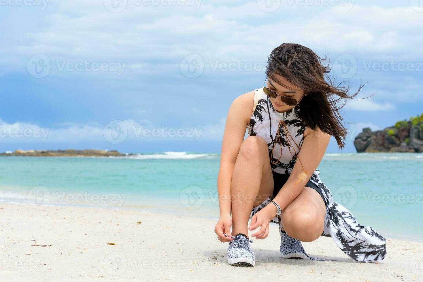 Woman binding rope sneakers on the beach, Thailand photo