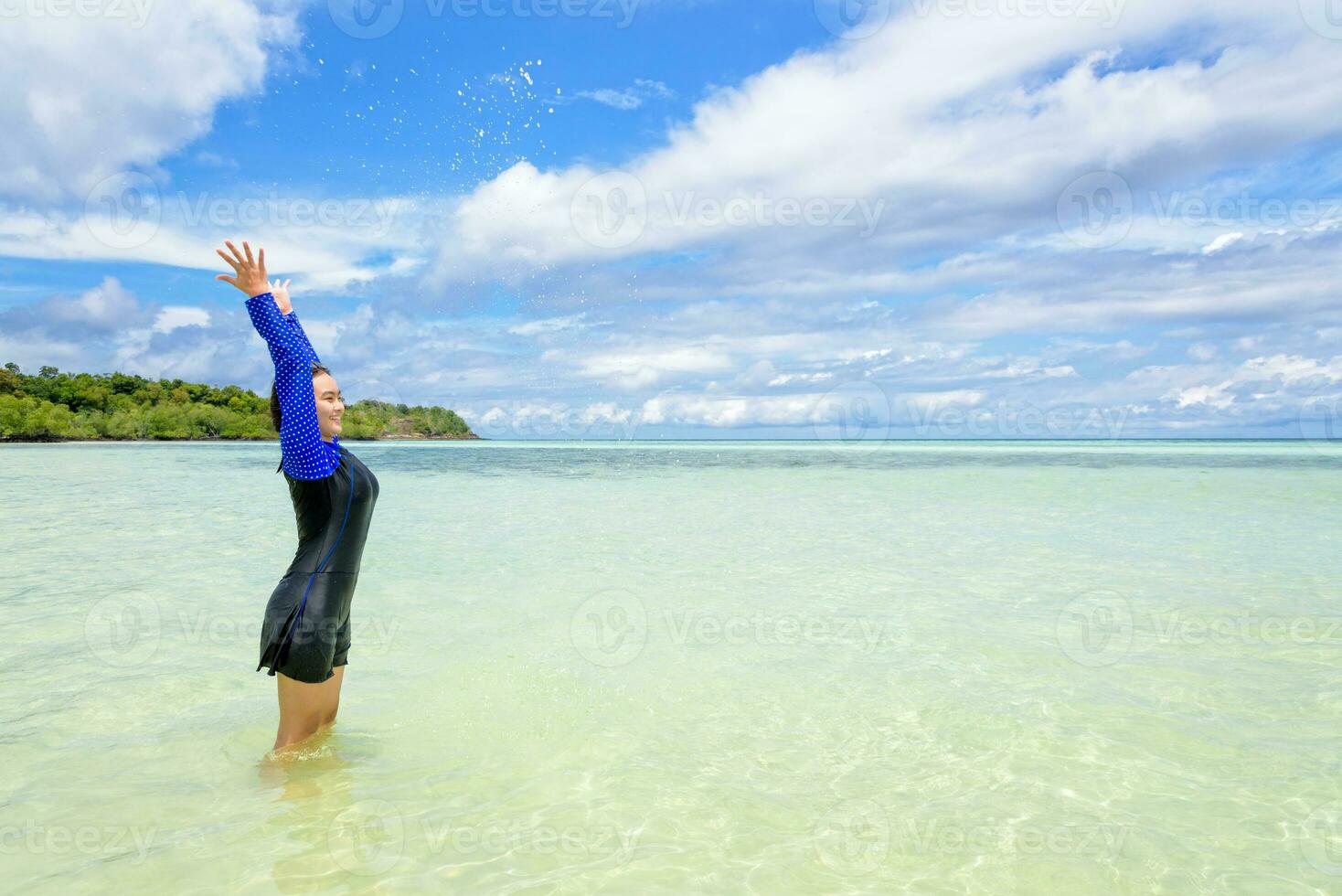 contento asiático adolescente niña jugar salpicaduras agua en el mar foto