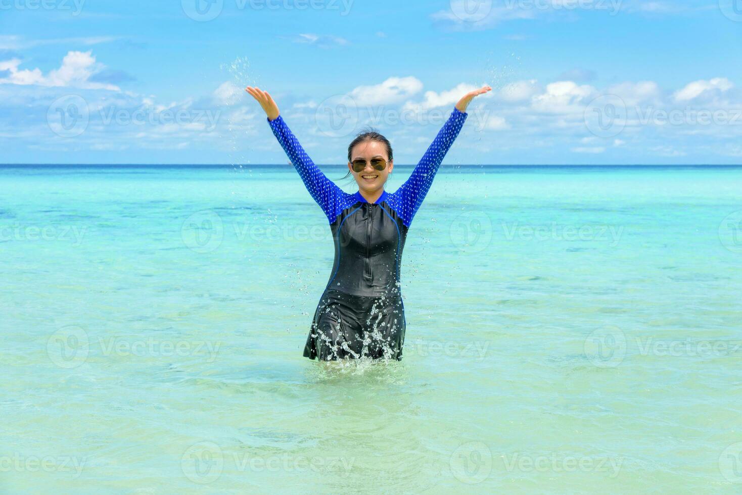 Happy asian teen girl play splashing water in the sea photo