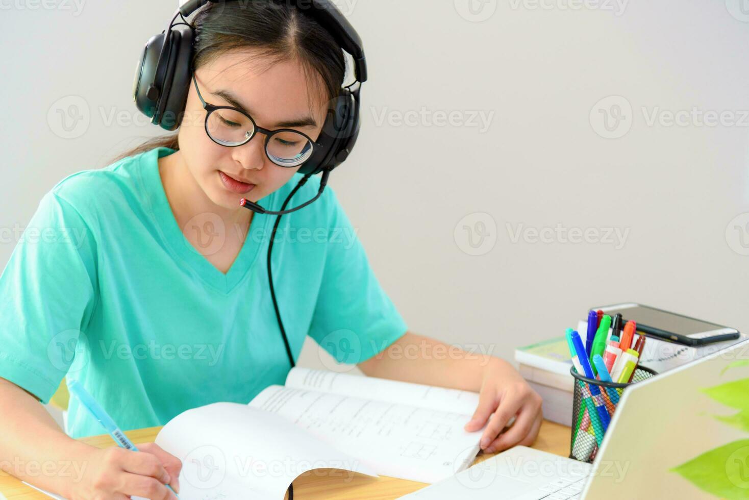 Asian woman writing notes at book learning online photo