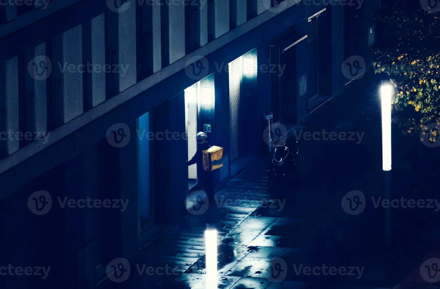 Food delivery person outside an apartment building at night photo