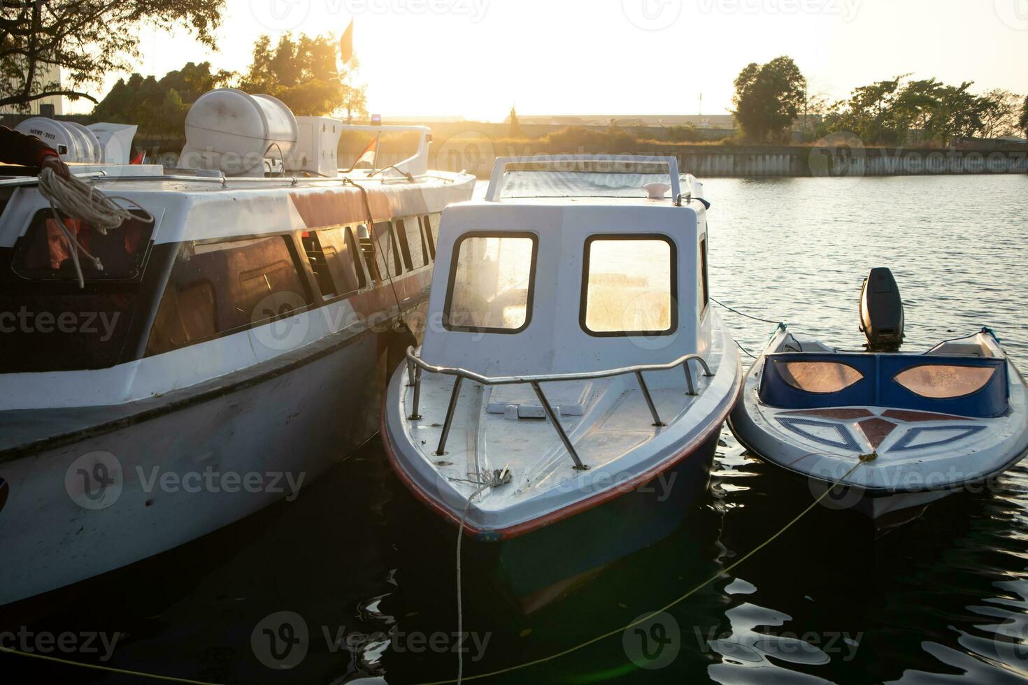 three boats docked in a harbor at sunset. photo