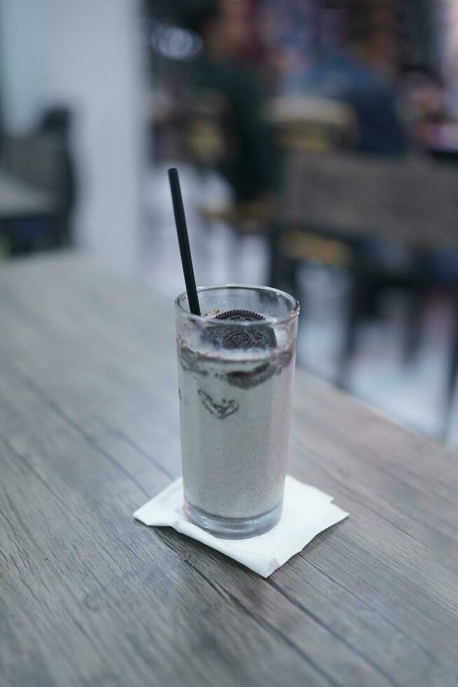 Chocolate milkshake with chocolate pieces and cake on top, cafe background atmosphere photo