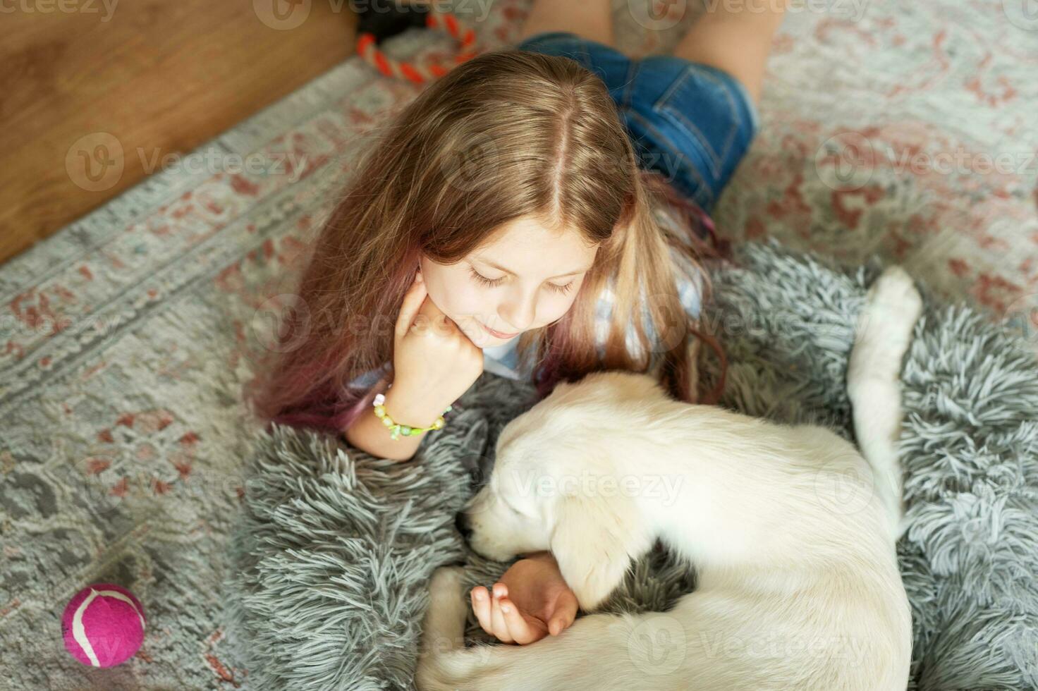 Little girl playing with a golden retriever puppy at home. photo