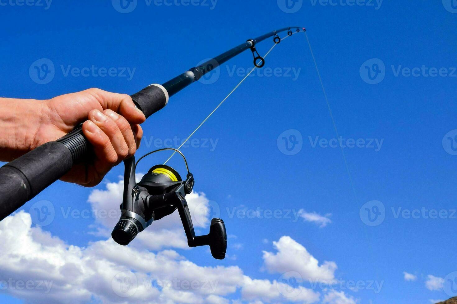 a person holding a fishing rod and reel photo