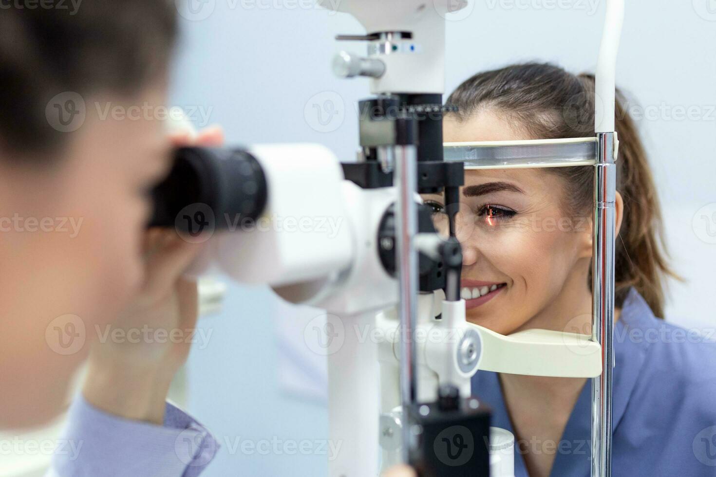 Female doctor ophthalmologist is checking the eye vision of attractive young woman in modern clinic. Doctor and patient in ophthalmology clinic. photo