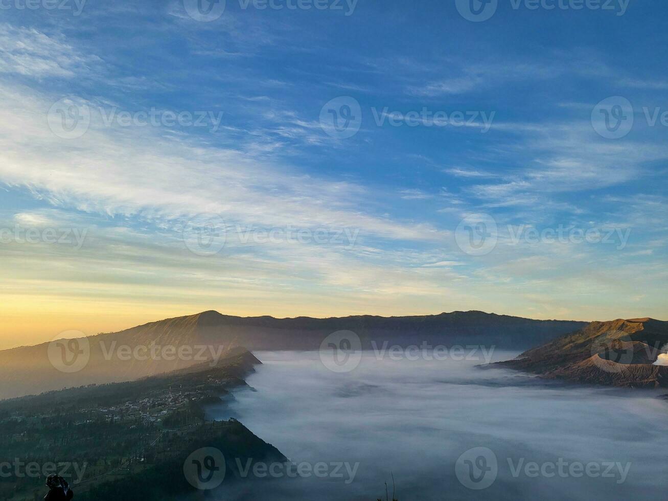 Sunrise view from Penanjakan 2 or Seruni point below can be seen as the fog begins to slowly shift to reveal a beautiful view of the sea of sand. photo