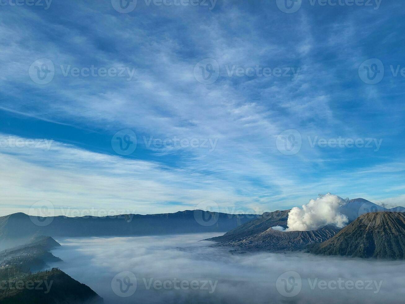 The clear sky is beautiful and blue with Mount Bromo still emitting volcanic smoke side by side with Mount Batok. The Sea of Sand plains began to appear because the fog began to disappear slowly photo