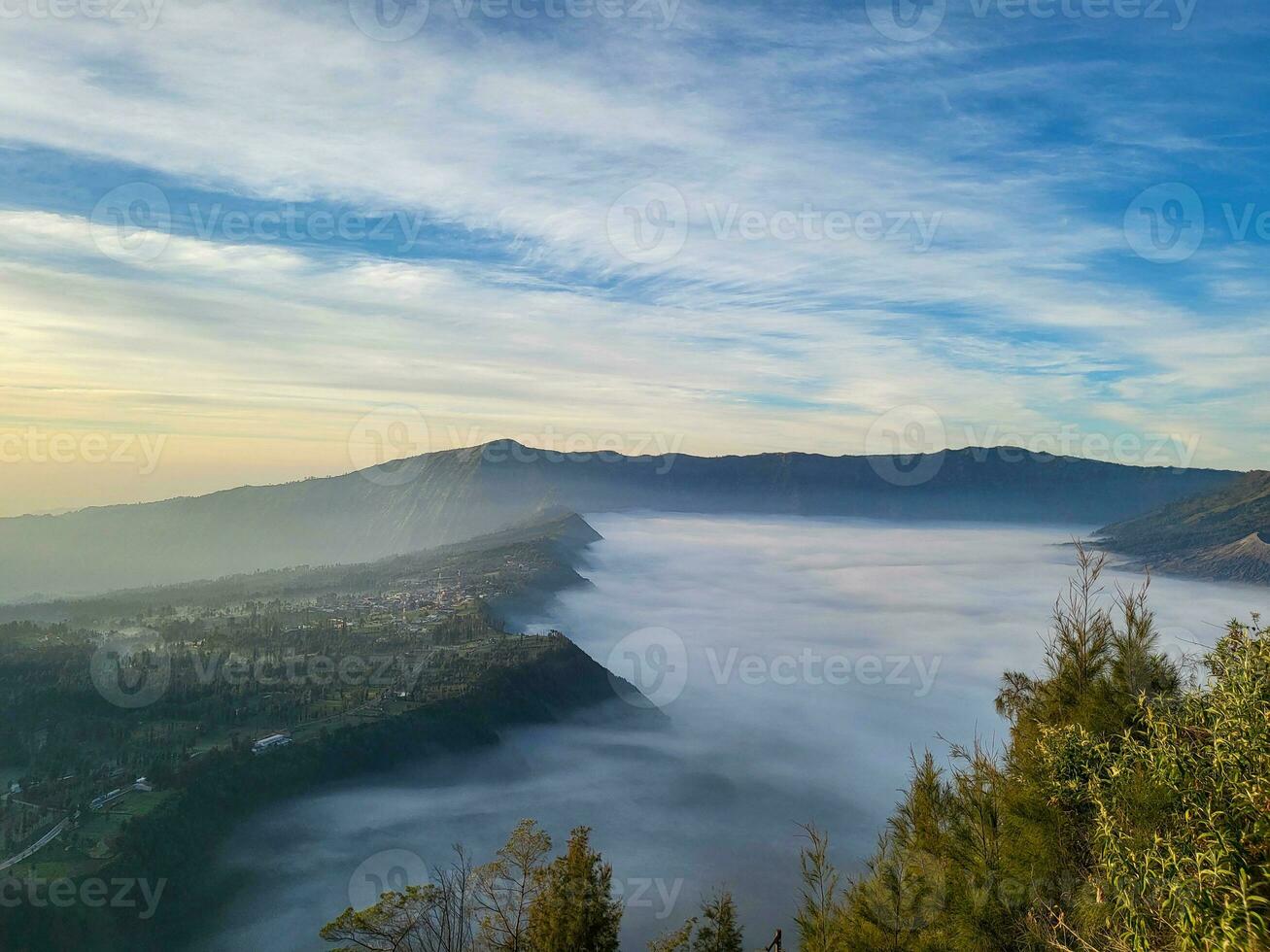 Sunrise view from Penanjakan 2 or Seruni point below can be seen as the fog begins to slowly shift to reveal a beautiful view of the sea of sand. photo