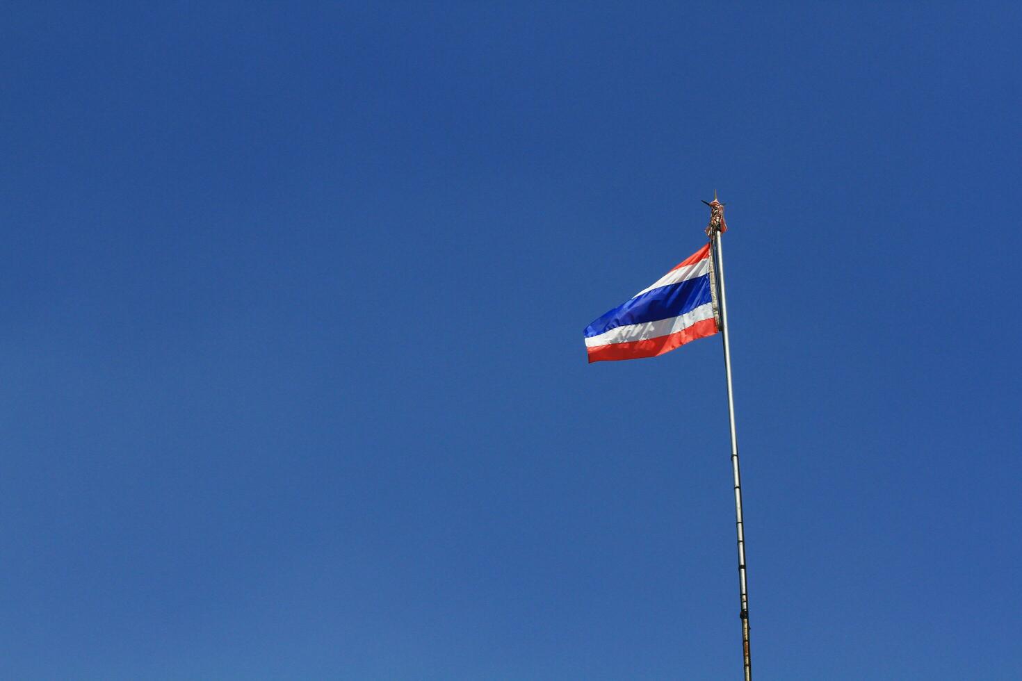 National Flag of Thailand is waving on pole with blue sky background photo