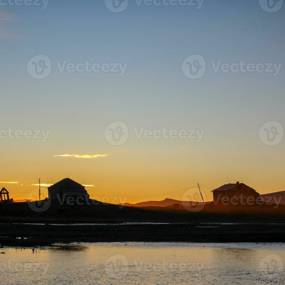 puesta de sol en contra el fondo de de madera casas en el isla foto