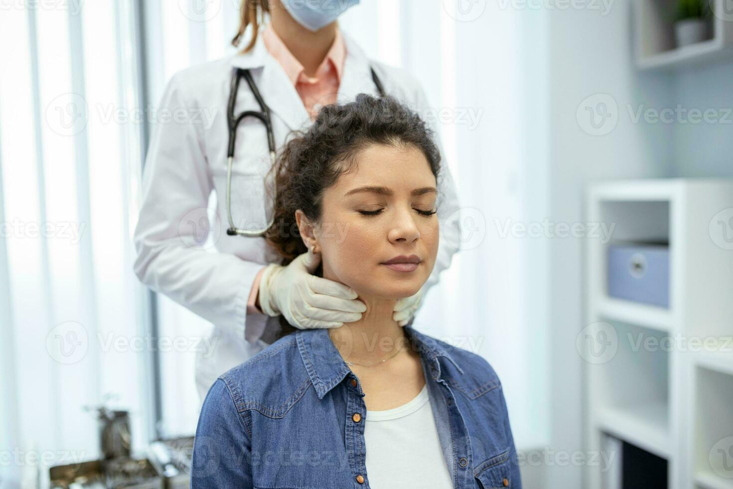 Endocrinologist examining throat of young woman in clinic. Women with thyroid gland test . Endocrinology, hormones and treatment. Inflammation of the sore throat photo