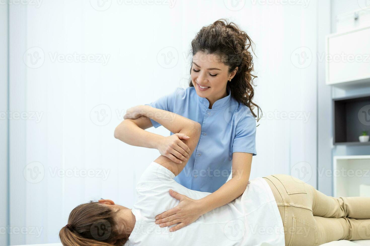 Close up of female osteopath doing shoulder blade therapy on young woman. photo
