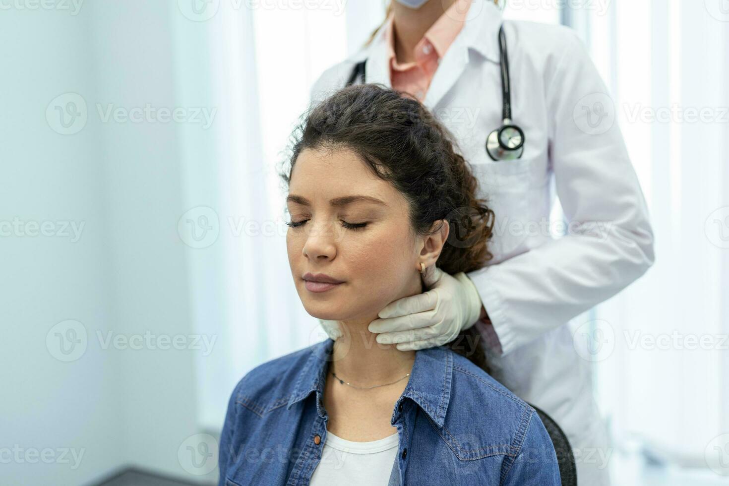 Endocrinologist examining throat of young woman in clinic. Women with thyroid gland test . Endocrinology, hormones and treatment. Inflammation of the sore throat photo