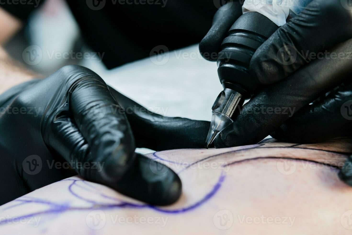 Professional tattoo artist makes a tattoo on the male leg photo