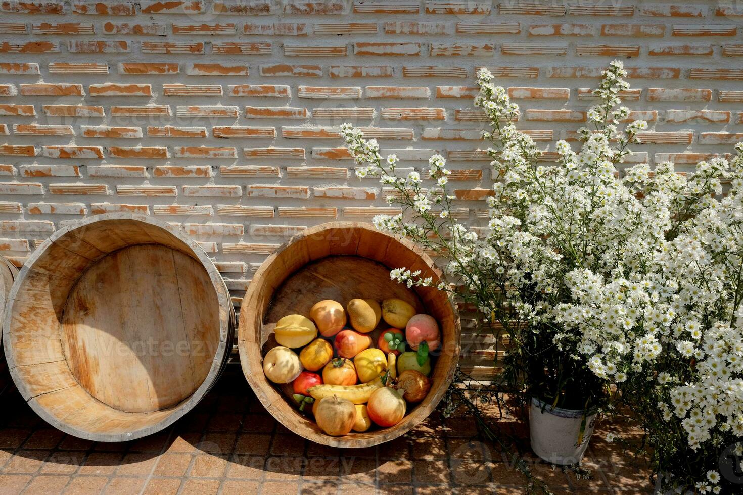 Blooming white flowers in vase and fruits in wood basket decorative for vintage brick wall photo