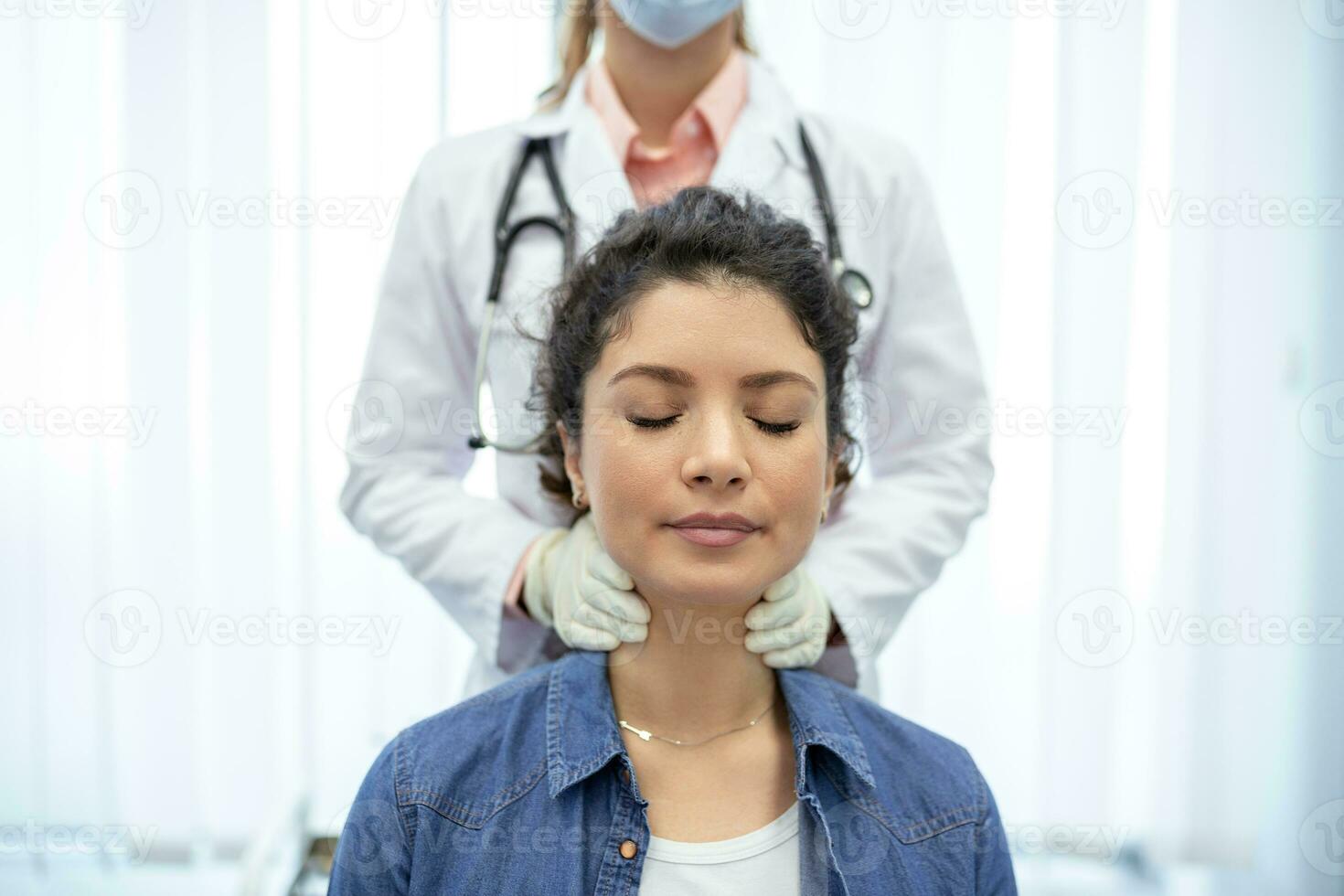 Endocrinologist examining throat of young woman in clinic. Women with thyroid gland test . Endocrinology, hormones and treatment. Inflammation of the sore throat photo