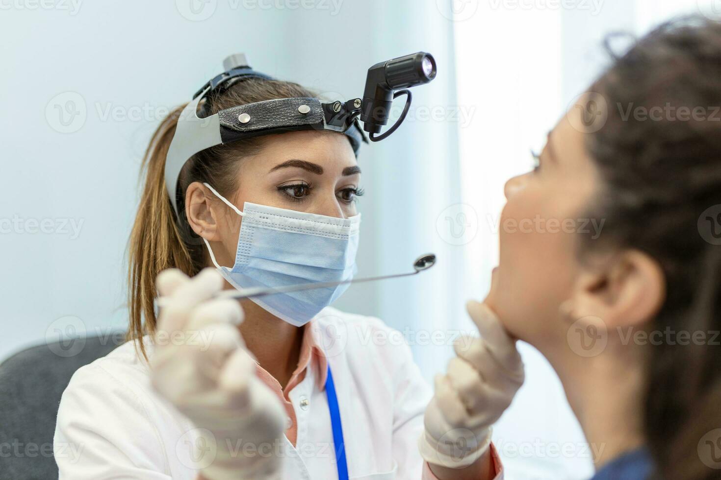 hembra paciente apertura su boca para el médico a Mira en su garganta. hembra médico examinando dolorido garganta de paciente en clínica. otorrinolaringólogo examina dolorido garganta de paciente. foto