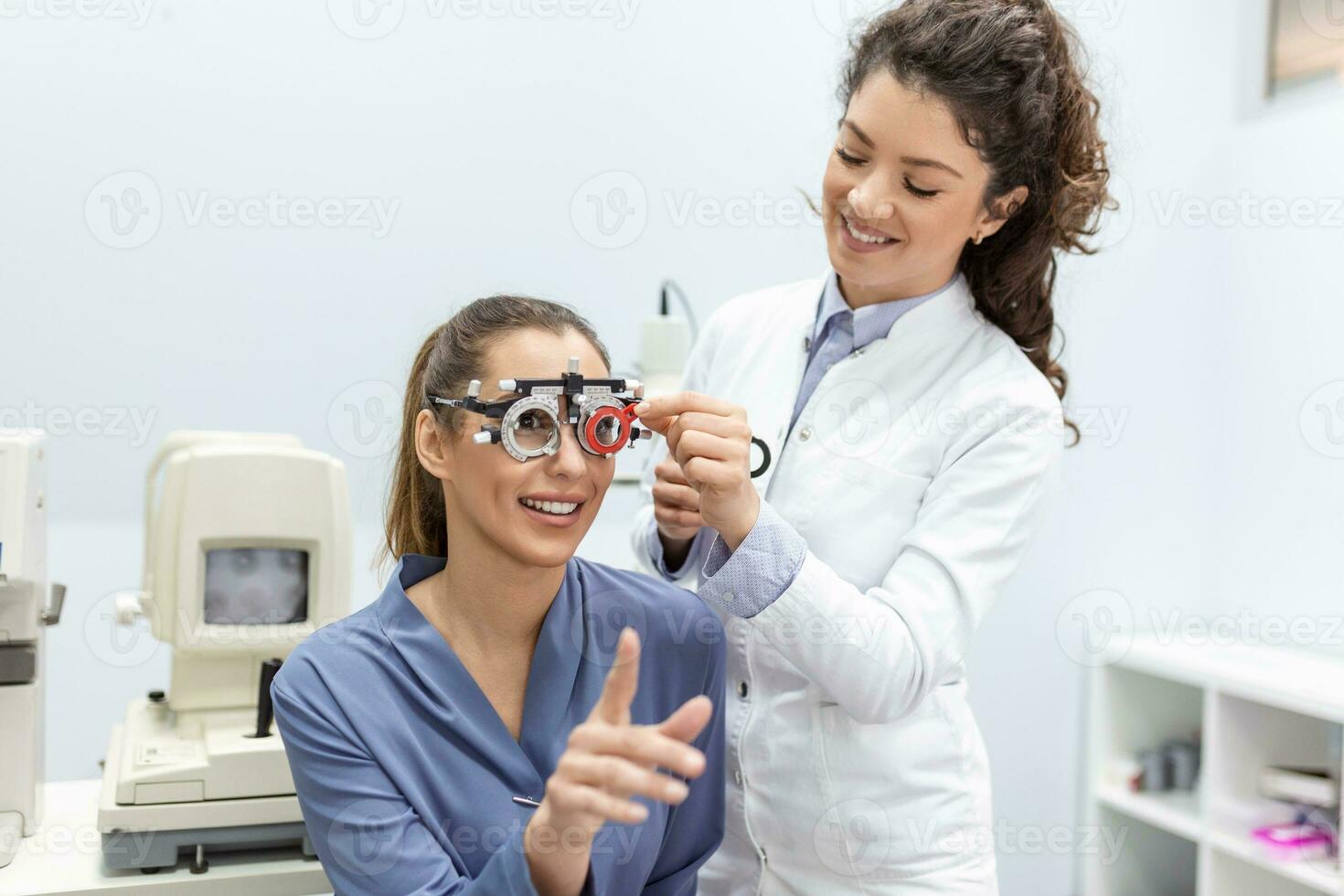 Optometrists changes lenses in trial frame to examine the vision of young woman patient vision at ophthalmology clinic, selective focus photo