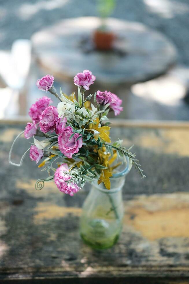 pequeño florecer rosado flores en vaso florero decorado en Clásico de madera mesa en natural jardín casa foto