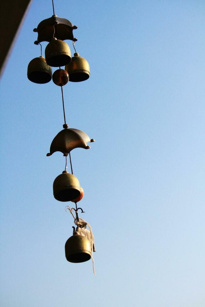 Gold brass Bells Hanging on pagoda in temple is located on the mountain for blue sky, Thailand photo