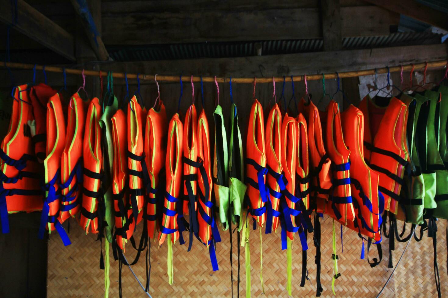 naranja vida chaleco chaquetas colgando en estante al aire libre para la seguridad y proteccion mientras utilizando en como nadando a el mar. foto