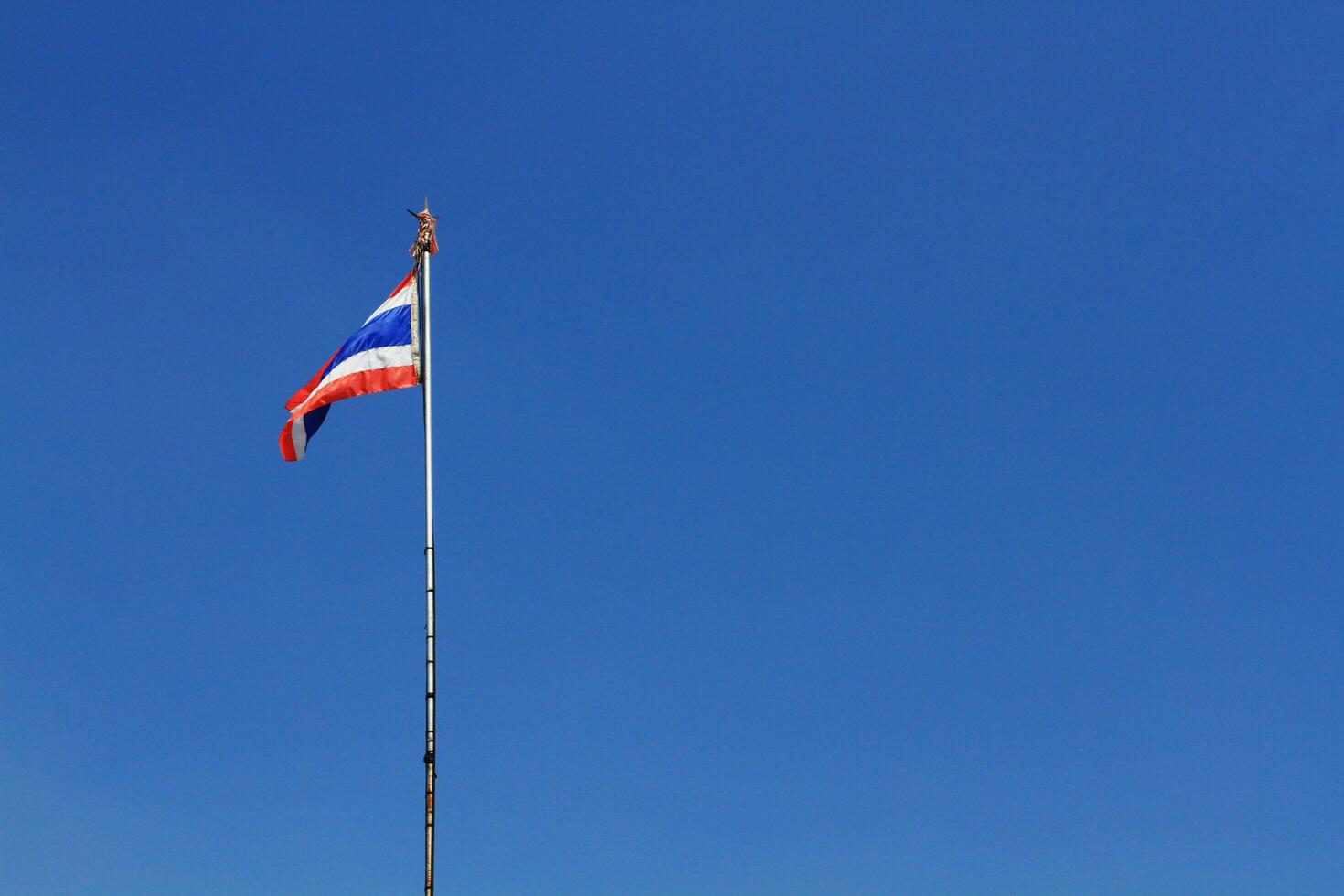 National Flag of Thailand is waving on pole with blue sky background photo