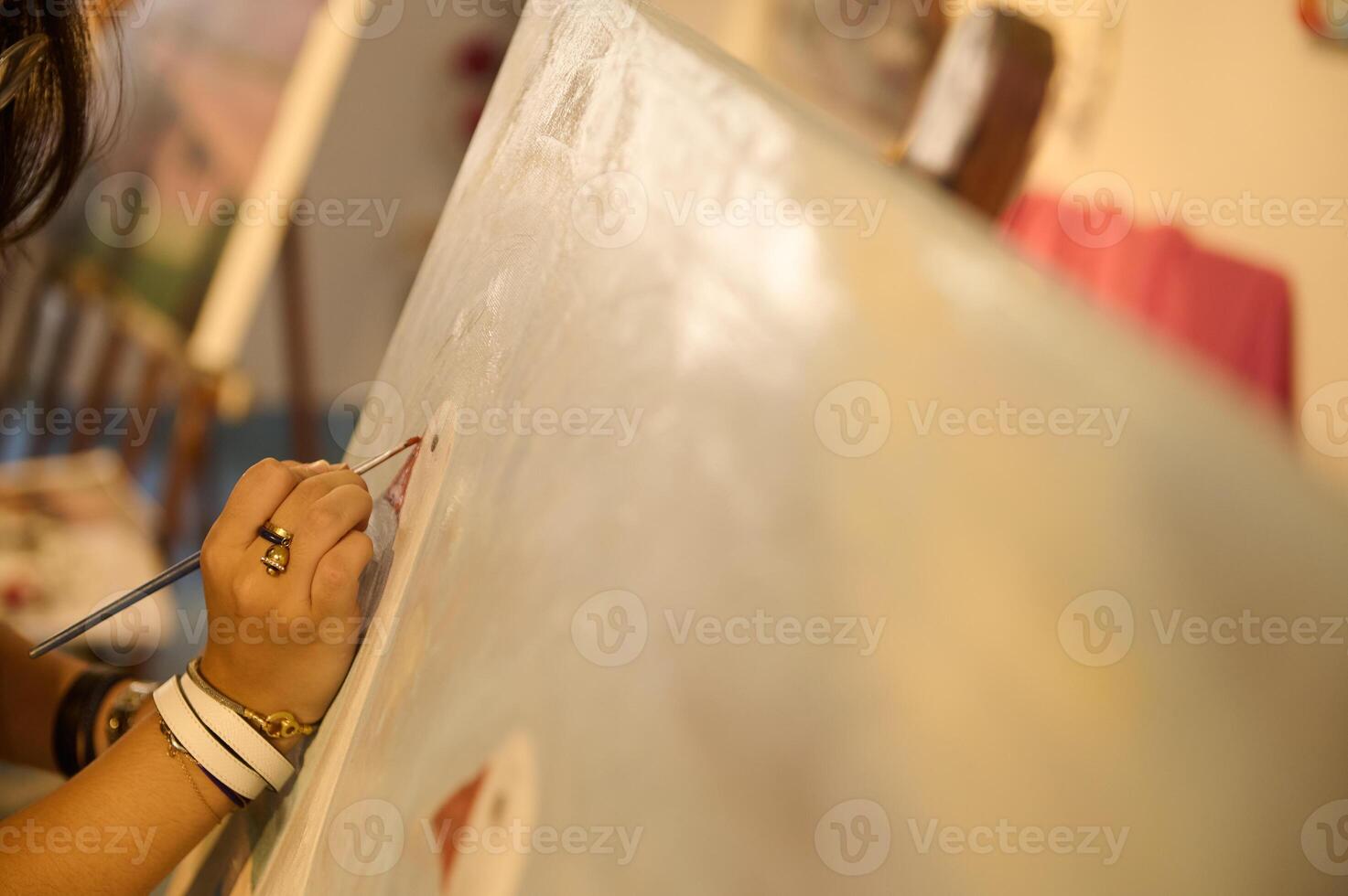 Close-up artist's hands works on painting on canvas, in creative art workshop, holds a palette with oil paints and brush photo