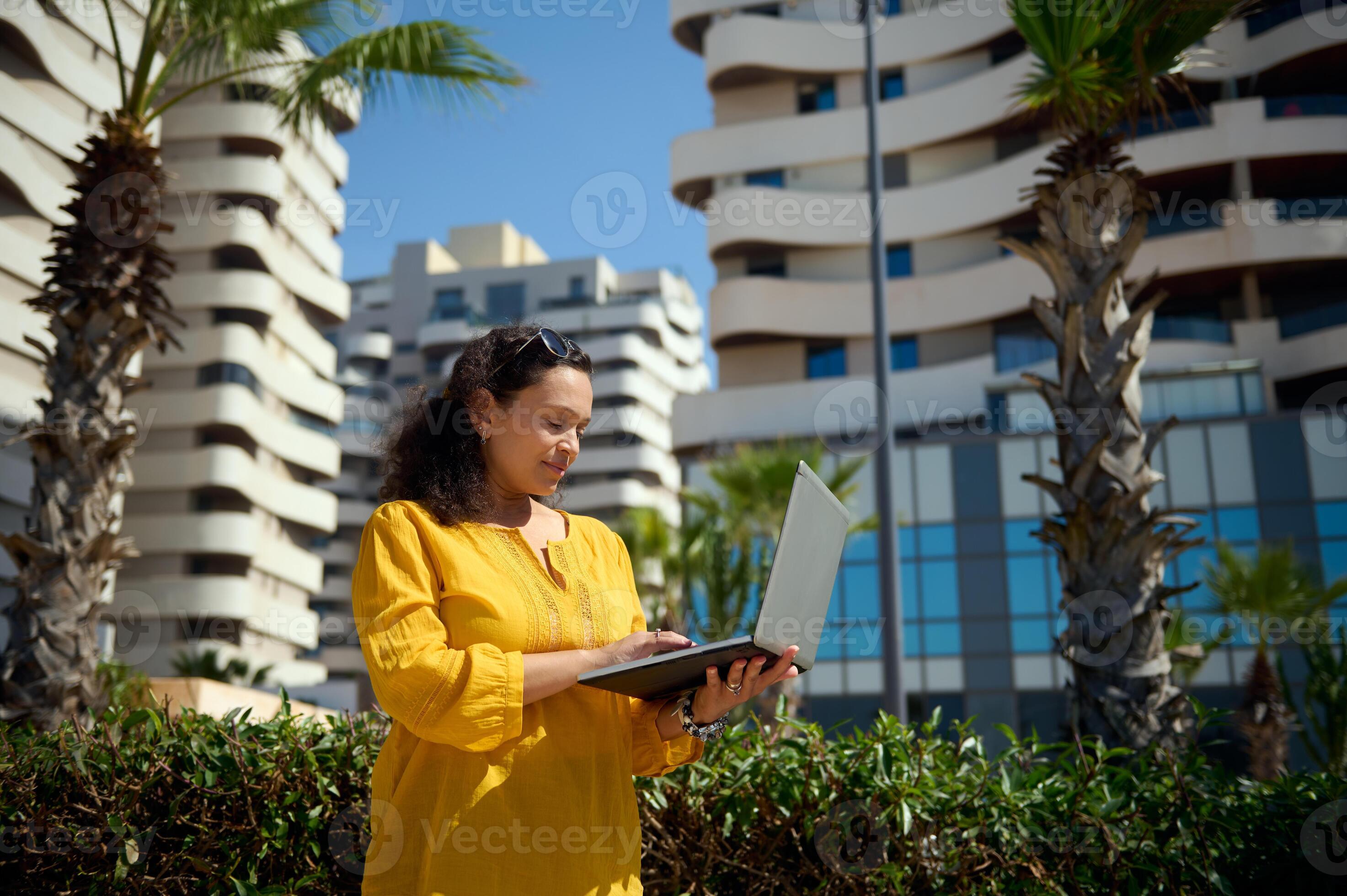 Charming female freelancer, real estate agent using laptop, standing