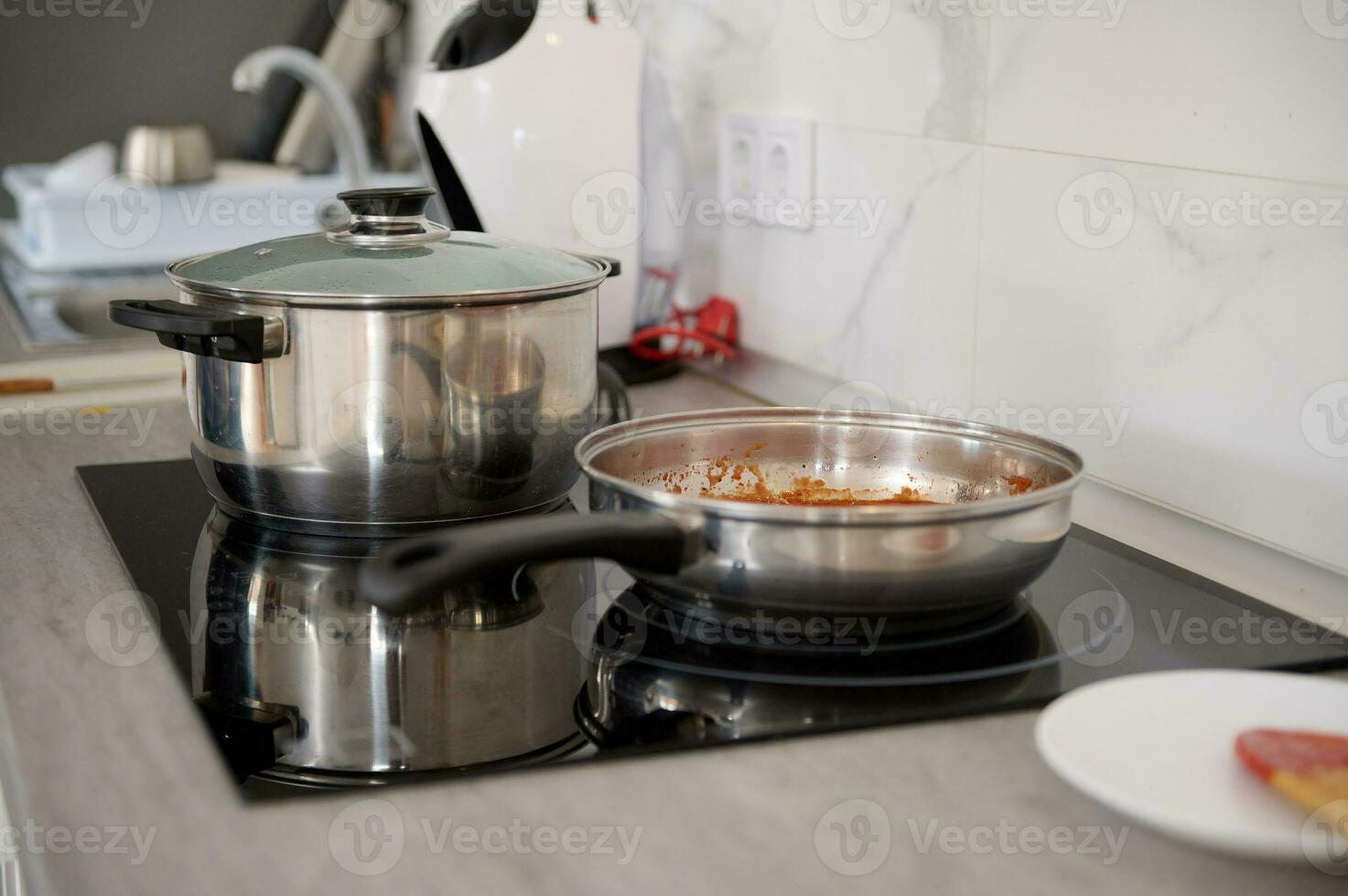 A stainless steel frying pan and saucepan on the electric stove in the home kitchen. Culinary concept. Food background photo