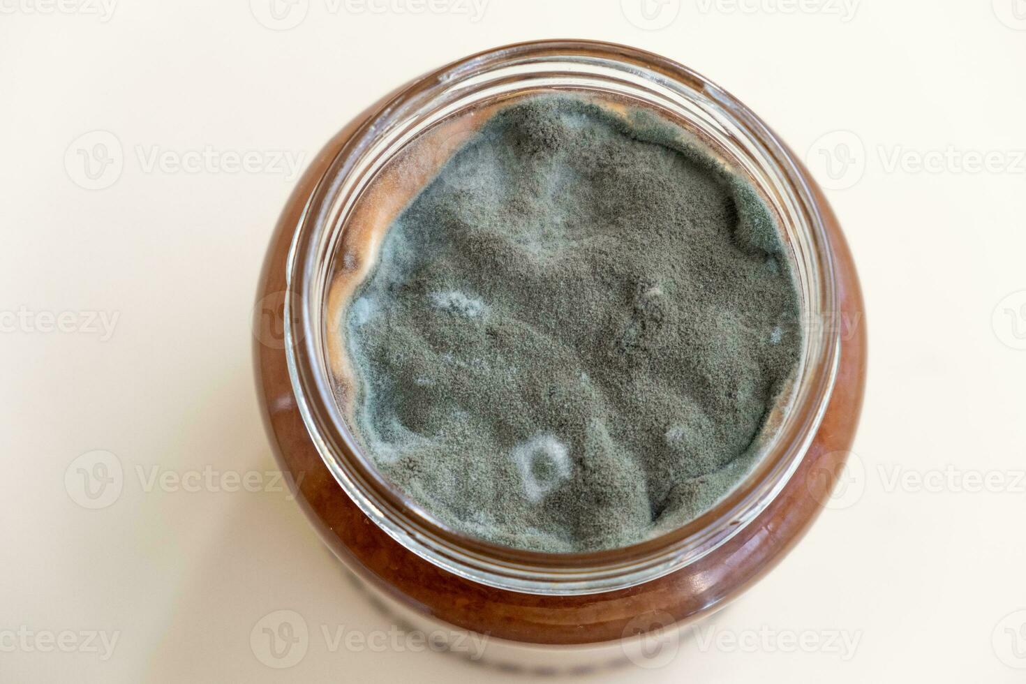 Open jar with sweet jam and mold on a white background. photo