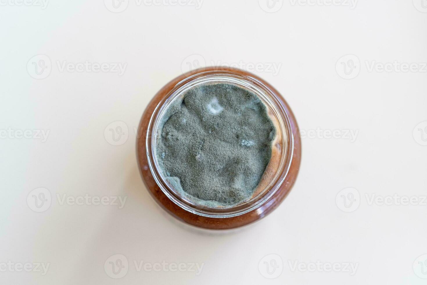 Open jar with sweet jam and mold on a white background. photo