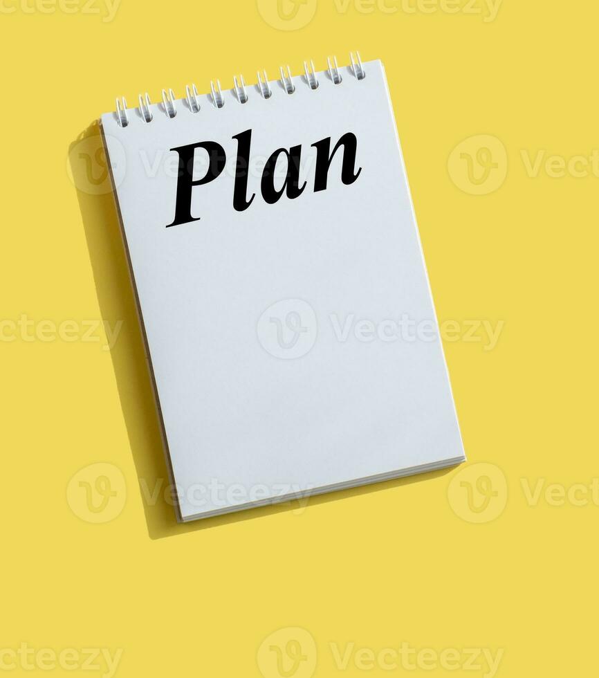 Inscription PLAN written on note paper on a bright yellow background photo