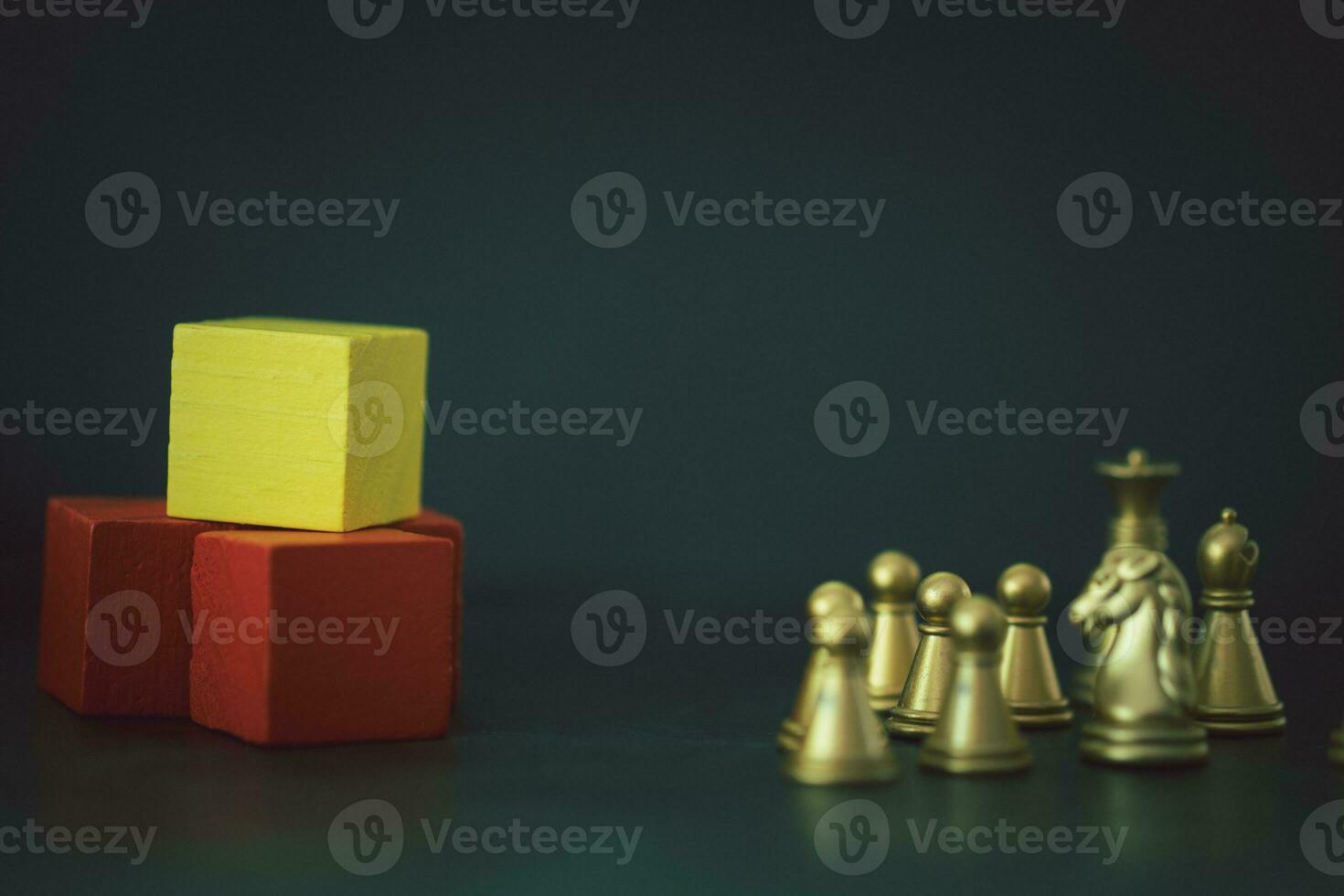 Golden chess pawn pieces on the ground with tower of wood block photo