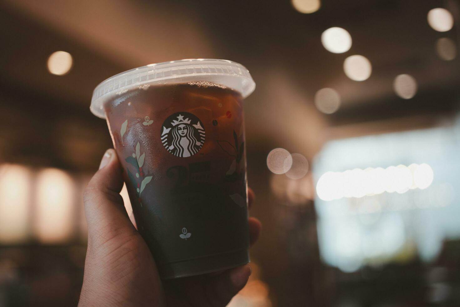 Bangkok, Thailand - October 16, 2023 Man holding a cup of  reusable cup cold  Americano 25th Anniversary, Starbucks Thailand. Limited-edition photo