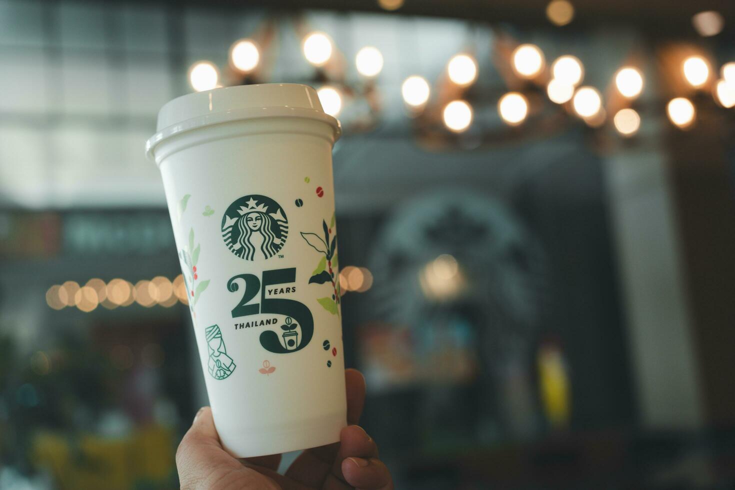 Bangkok, Thailand - October 17, 2023 Man holding reusable cup, 25th Anniversary, Starbucks Thailand, get 1 free. Limited-edition photo