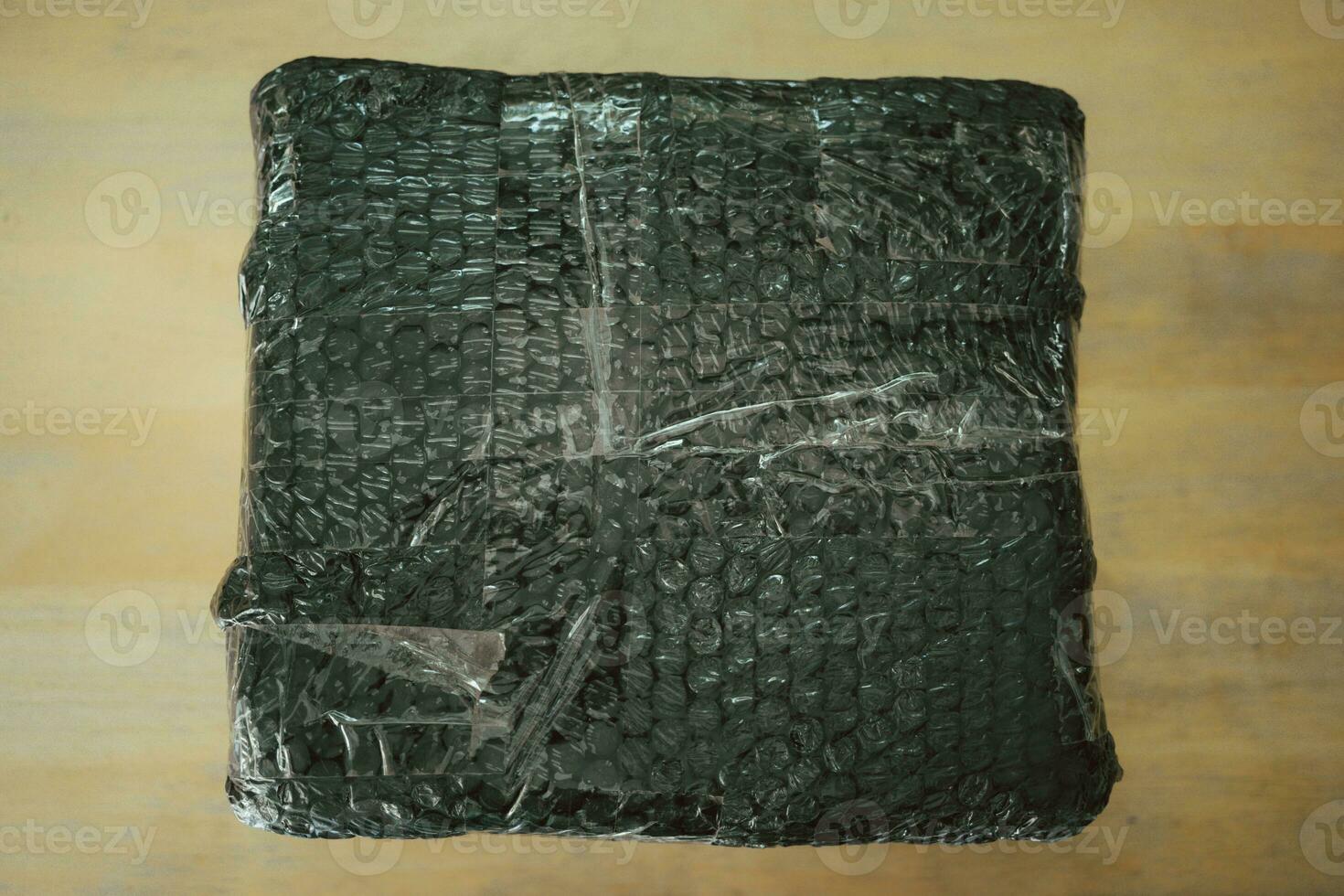 Black bubble wrapped with adhesive tape for packing fragile items. Safe delivery. photo