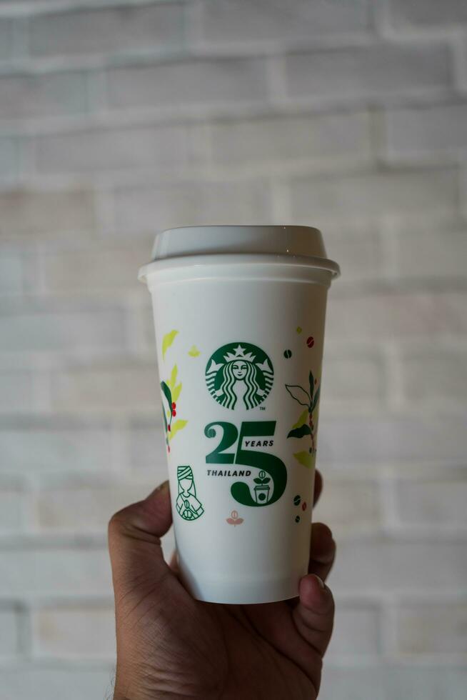 Bangkok, Thailand - October 16, 2023 Asian man holding a reusable cup with a special 25th Anniversary. photo