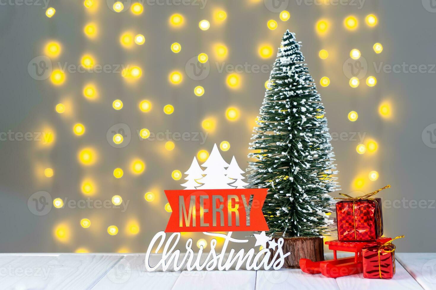 Christmas tree, gift boxes and wooden lettering Merry Christmas on light bokeh background. photo