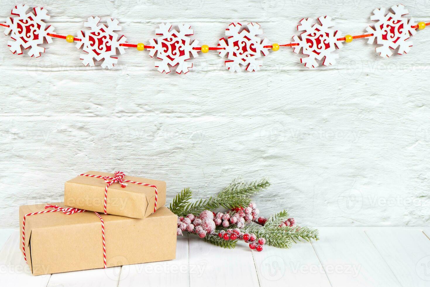 Christmas tree branch and gift boxes on white brick background with snowflakes garland photo