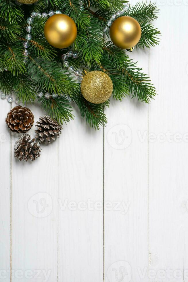 Christmas tree branch decorated with golden balls and gift box on white wooden background photo