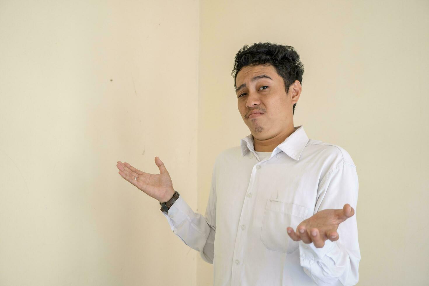 Young Indonesian curly man wear white clothes with i don't know pose. photo