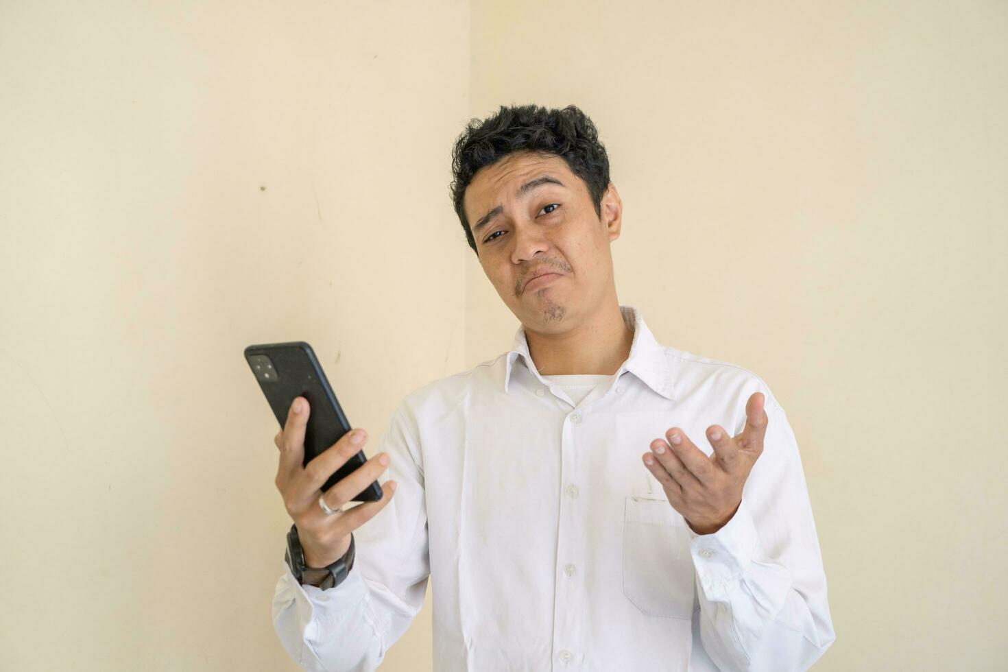 Indonesian office employee wear white clothes with why expression when check the smartphone. photo