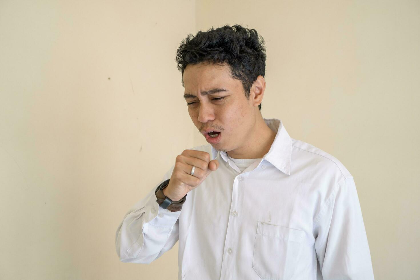 Young Indonesian curly man wear white clothes with cough pose. photo